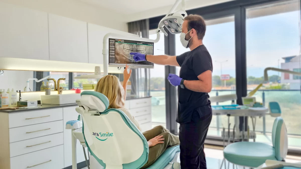 Modern dental treatment at Lara Smile Dental Clinic in Turkey, where a skilled dentist shows a patient a digital panoramic dental image. Highlighting the expertise in Turkey teeth treatments in a spacious and well-lit examination room.