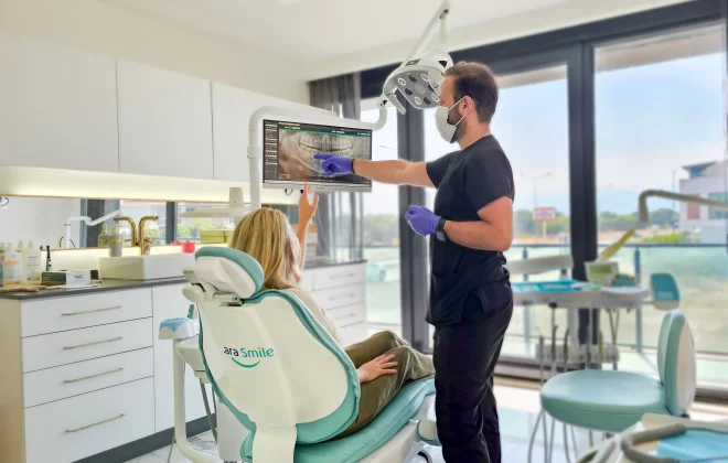 Modern dental treatment at Lara Smile Dental Clinic in Turkey, where a skilled dentist shows a patient a digital panoramic dental image. Highlighting the expertise in Turkey teeth treatments in a spacious and well-lit examination room.